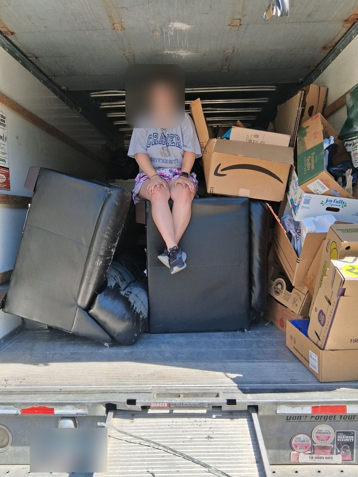 Crew member sitting in a moving truck loaded with furniture and boxes