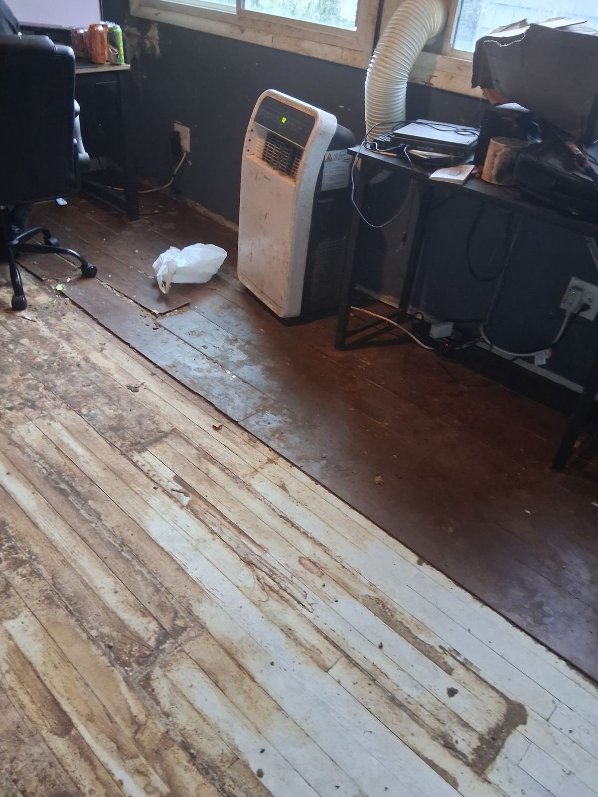 After: Same room cleared to the bare floorboards, with the AC unit and desk still in place